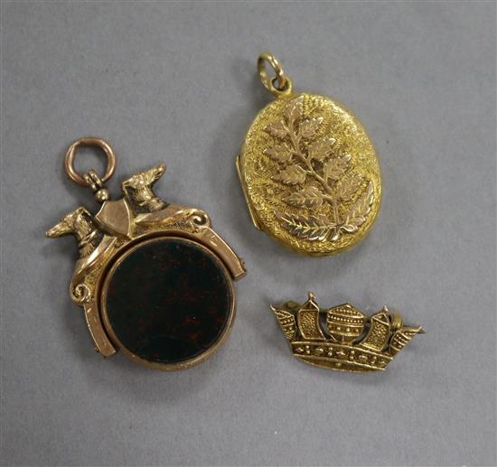 A Victorian 9ct gold and carnelian set spinning fob seal, a 9ct coronet brooch and a yellow metal locket.
